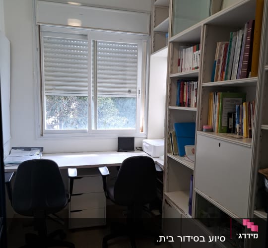 חדר עבודה עם שולחן, כיסאות ומדפים מלאים בספרים